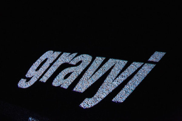An image of gravel with the Jèrriais word for gravel in large letters, projected onto the gravel.
