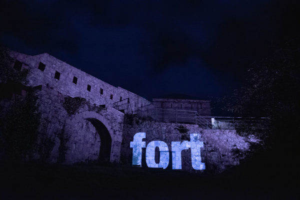 An image of an outdoor wall at Fort Leicester with the Jèrriais word for fort in large letters, projected onto the wall.