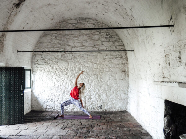 Woman does yoga pose against white lime wash wall