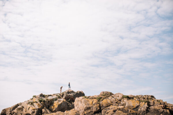 two people walking across rocks